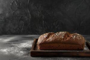 Freshly baked dark bread on a wooden tray over dark background photo