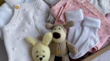 Baby and child clothes and knitted toys in carton box. video