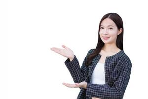 joven asiático profesional trabajando mujer quien usa negro traje con tirantes en dientes es señalando mano a presente alguna cosa mientras aislado blanco antecedentes. foto