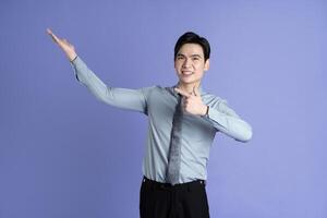 Portrait of Asian male businessman posing on purple background photo