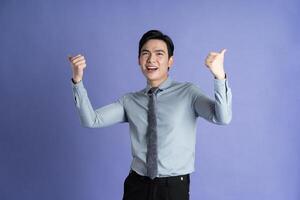 Portrait of Asian male businessman posing on purple background photo