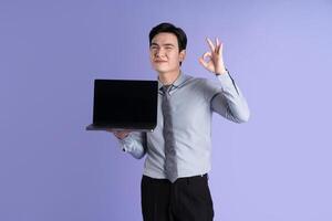 Portrait of Asian male businessman posing on purple background photo