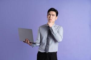 Portrait of Asian male businessman posing on purple background photo