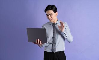 Portrait of Asian male businessman posing on purple background photo