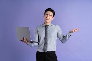 Portrait of Asian male businessman posing on purple background photo