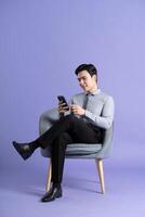 Portrait of Asian business man sitting on sofa, isolated on purple background photo