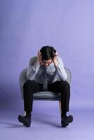 Portrait of Asian business man sitting on sofa, isolated on purple background photo