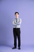 Portrait of Asian male businessman standing and posing on purple background photo