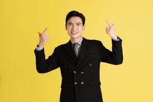 Portrait of Asian male businessman. wearing a suit and posing on a yellow background photo