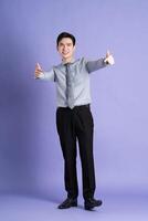 Portrait of Asian male businessman standing and posing on purple background photo