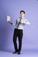 Portrait of Asian male businessman standing and posing on purple background photo