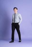 Portrait of Asian male businessman standing and posing on purple background photo