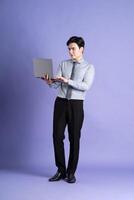 Portrait of Asian male businessman standing and posing on purple background photo