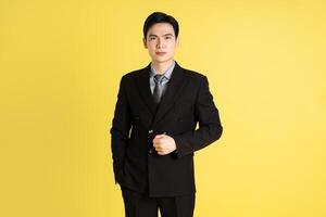 Portrait of Asian male businessman. wearing a suit and posing on a yellow background photo