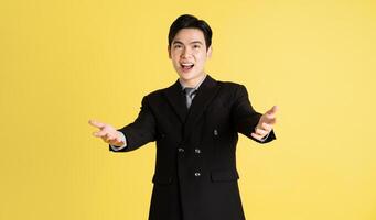 Portrait of Asian male businessman. wearing a suit and posing on a yellow background photo