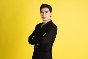 Portrait of Asian male businessman. wearing a suit and posing on a yellow background photo