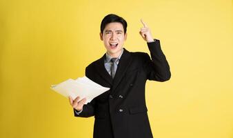 Portrait of Asian male businessman. wearing a suit and posing on a yellow background photo