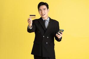 Portrait of Asian male businessman. wearing a suit and posing on a yellow background photo