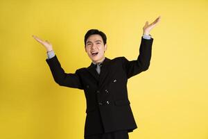 Portrait of Asian male businessman. wearing a suit and posing on a yellow background photo