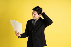 retrato de asiático masculino empresario. vistiendo un traje y posando en un amarillo antecedentes foto