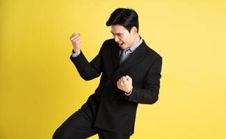 retrato de asiático masculino empresario. vistiendo un traje y posando en un amarillo antecedentes foto