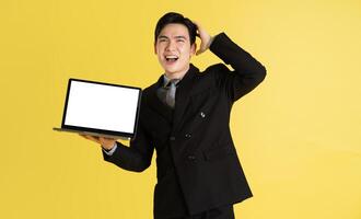 Portrait of Asian male businessman. wearing a suit and posing on a yellow background photo