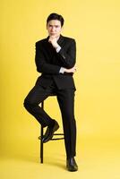 retrato de asiático masculino empresario. vistiendo un traje y posando en un amarillo antecedentes foto
