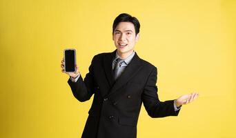 Portrait of Asian male businessman. wearing a suit and posing on a yellow background photo