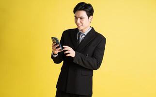 Portrait of Asian male businessman. wearing a suit and posing on a yellow background photo