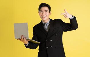 Portrait of Asian male businessman. wearing a suit and posing on a yellow background photo