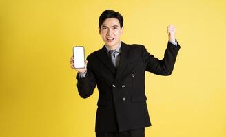 Portrait of Asian male businessman. wearing a suit and posing on a yellow background photo