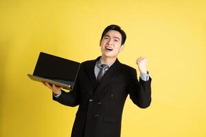 Portrait of Asian male businessman. wearing a suit and posing on a yellow background photo