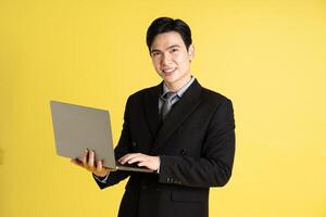 Portrait of Asian male businessman. wearing a suit and posing on a yellow background photo