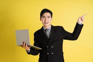 Portrait of Asian male businessman. wearing a suit and posing on a yellow background photo