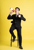 Portrait of Asian male businessman. wearing a suit and posing on a yellow background photo