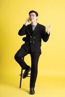 Portrait of Asian male businessman. wearing a suit and posing on a yellow background photo