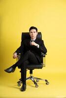 Portrait of Asian male businessman. wearing a suit and posing on a yellow background photo