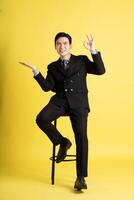 Portrait of Asian male businessman. wearing a suit and posing on a yellow background photo