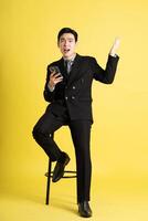 Portrait of Asian male businessman. wearing a suit and posing on a yellow background photo