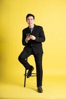 retrato de asiático masculino empresario. vistiendo un traje y posando en un amarillo antecedentes foto