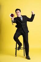 Portrait of Asian male businessman. wearing a suit and posing on a yellow background photo