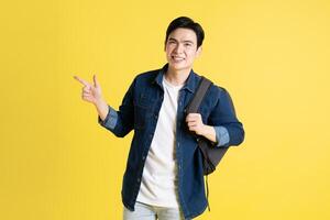 Portrait of Asian male student posing on yellow background photo