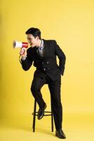 Portrait of Asian male businessman. wearing a suit and posing on a yellow background photo