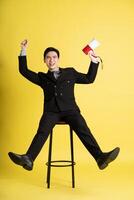 Portrait of Asian male businessman. wearing a suit and posing on a yellow background photo