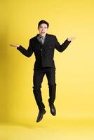 Portrait of Asian male businessman. wearing a suit and posing on a yellow background photo