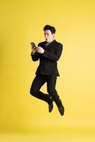 Portrait of Asian male businessman. wearing a suit and posing on a yellow background photo