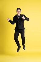 Portrait of Asian male businessman. wearing a suit and posing on a yellow background photo