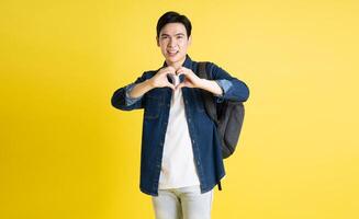 Portrait of Asian male student posing on yellow background photo