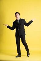 Portrait of Asian male businessman. wearing a suit and posing on a yellow background photo