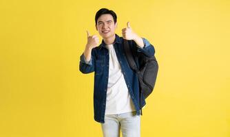 Portrait of Asian male student posing on yellow background photo